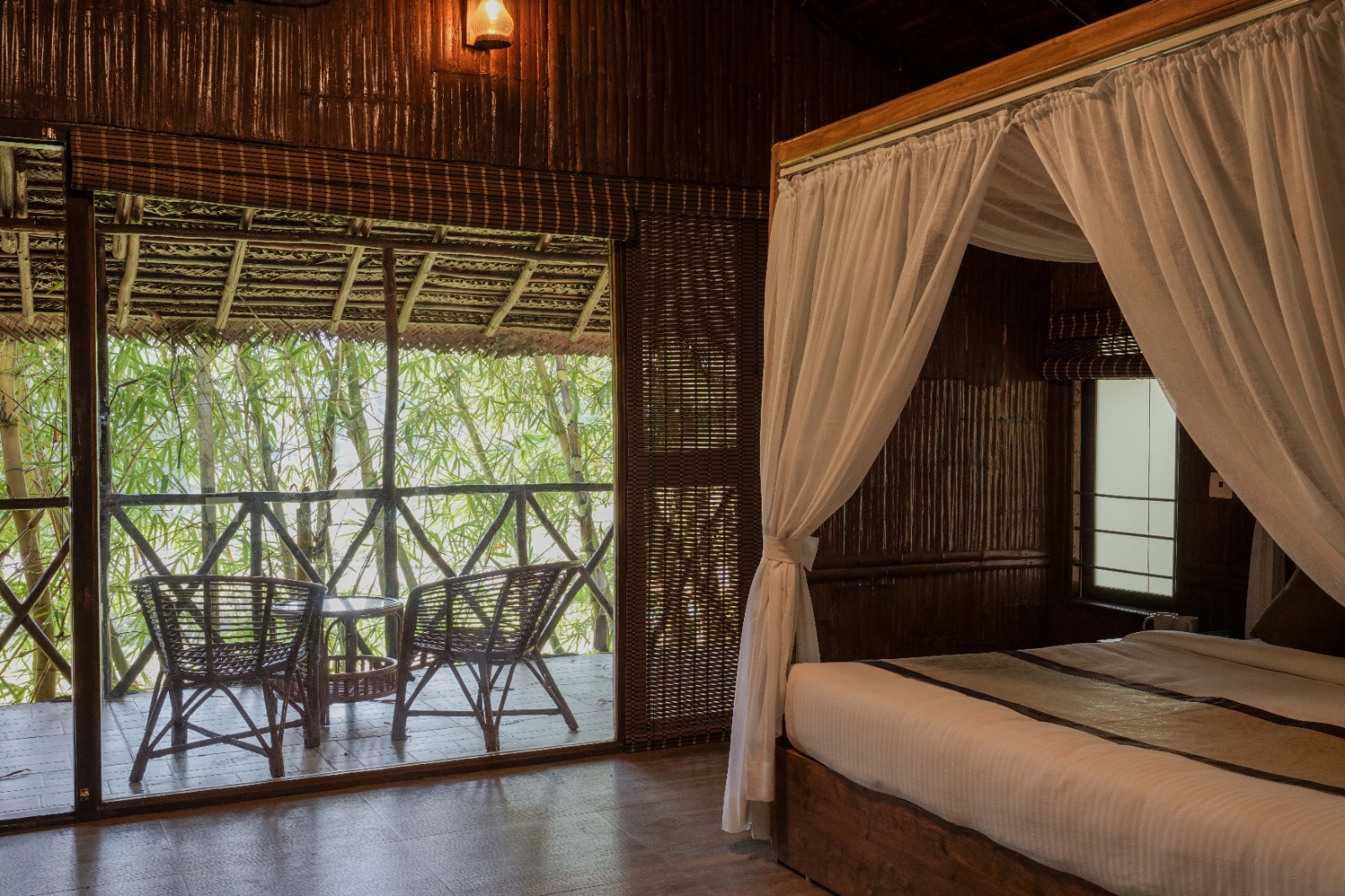 Canopy bed with sheer white drapes opening to the forest balcony